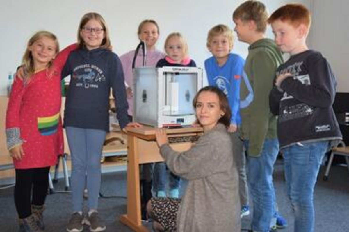 7 Kinder und 1 Lehrerin am 3D-Drucker