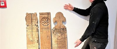 2023-04-28_Fund Landesmuseum Der Finder Niels Peters und sein Fund: Auf der mittleren und der rechten Wange sind Rosettenschnitzereien. Die Inschrift auf der rechten Wange verweist vermutlich auf die Stifter der Gestühlswangen. Foto: Dithmarscher Landesmuseum