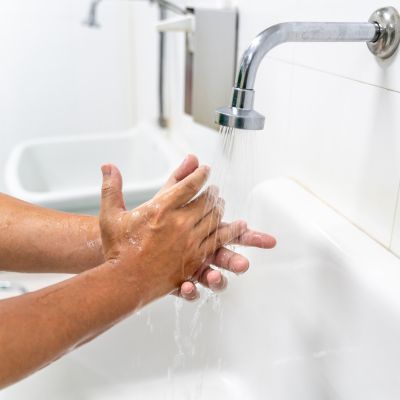 Bild zeigt Hände, die unter einem Wasserhahn gewaschen werden